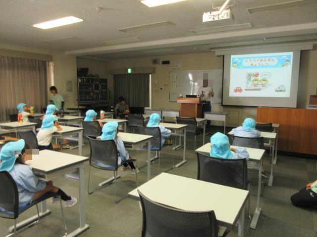 交通安全教室で園児が道路の歩き方の話を聞いている様子