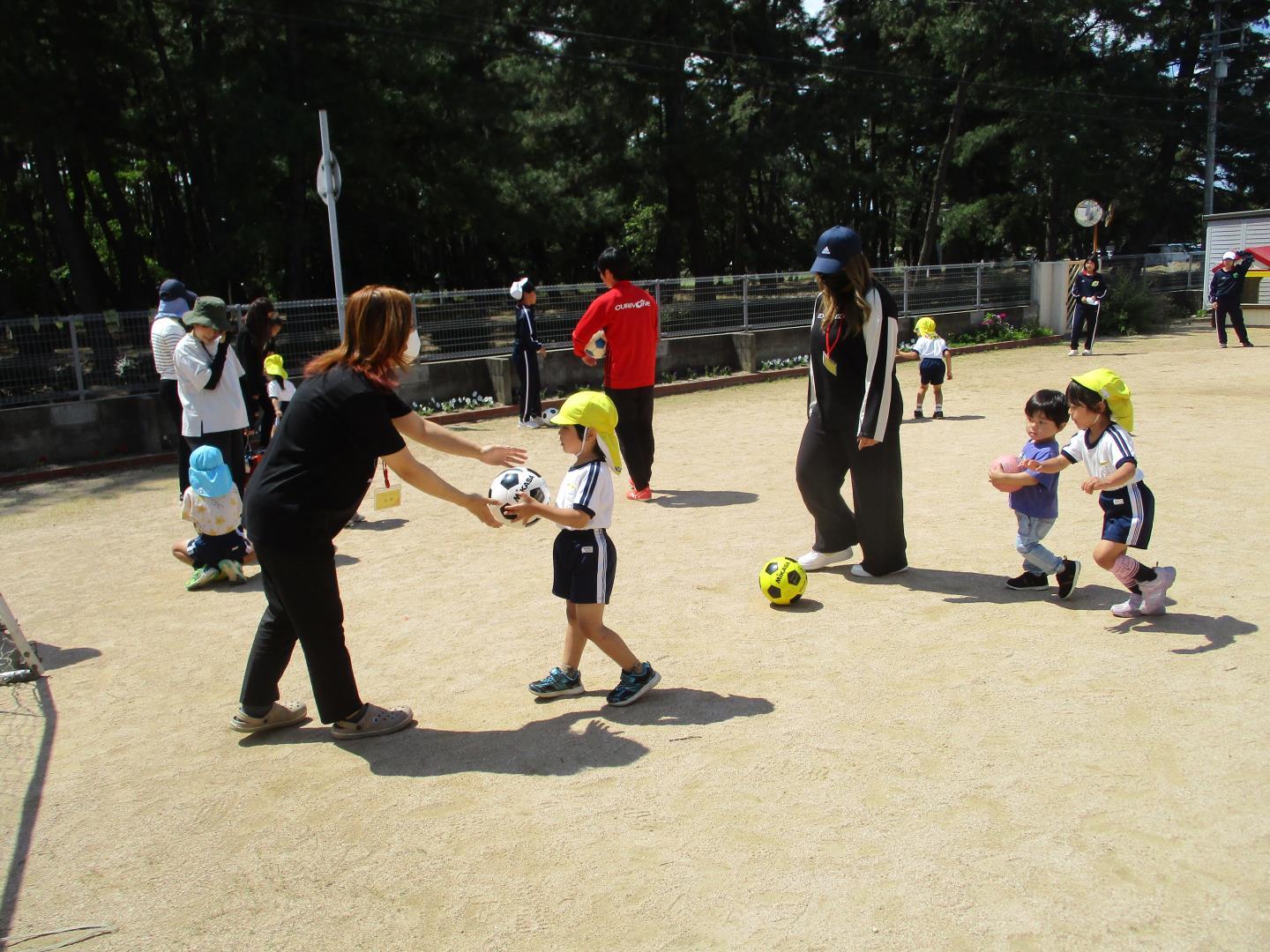 子ども達が保護者の方と一緒にサッカーボールを使って遊んでいるところ。
