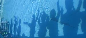 プールの水面に幼児の影が映っている
