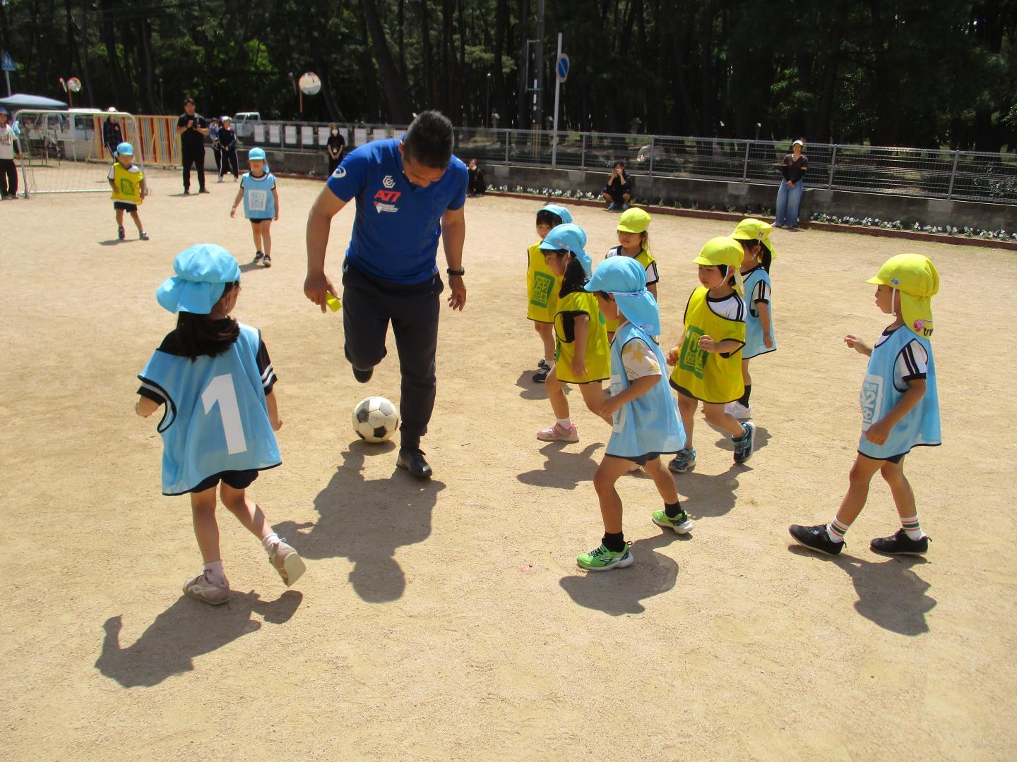サッカーコーチと一緒にユニフォームを着て試合をしている様子。