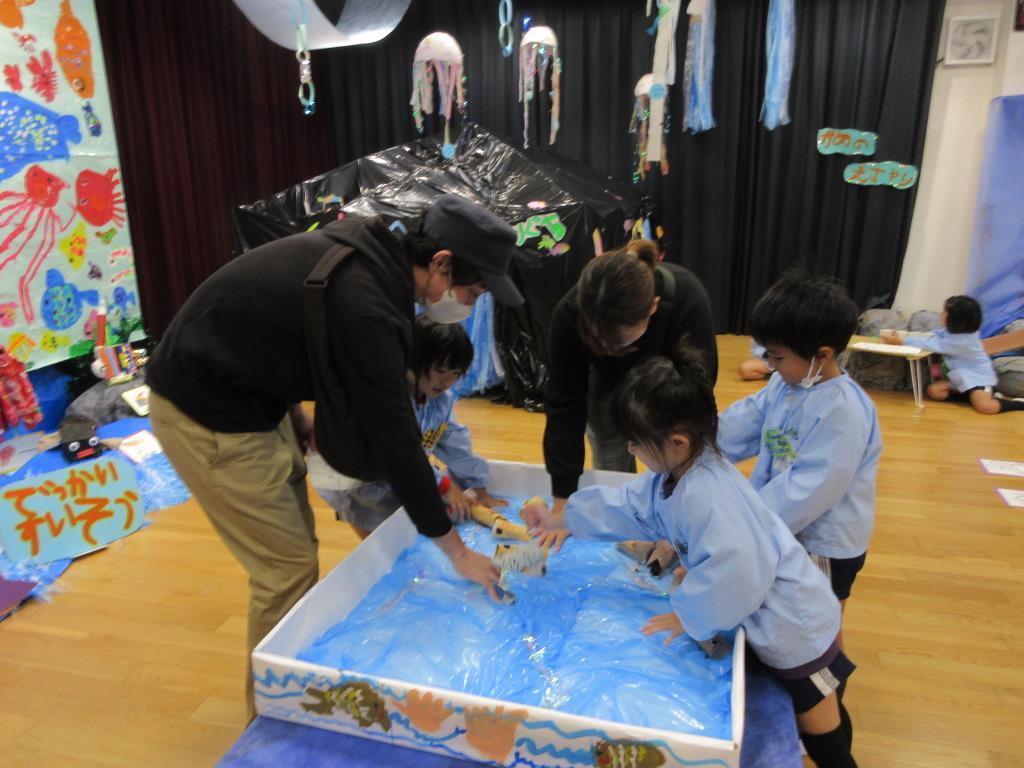 水族館ごっこで飼育員さんになり、お客さんにドクターフィッシュを体験してもらっている様子。