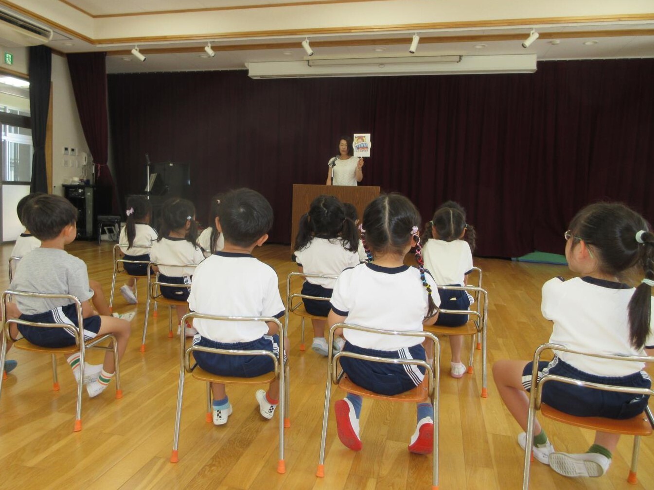 1学期の終業式に参加し、園長先生から夏休みの約束事の話を聞いている様子。