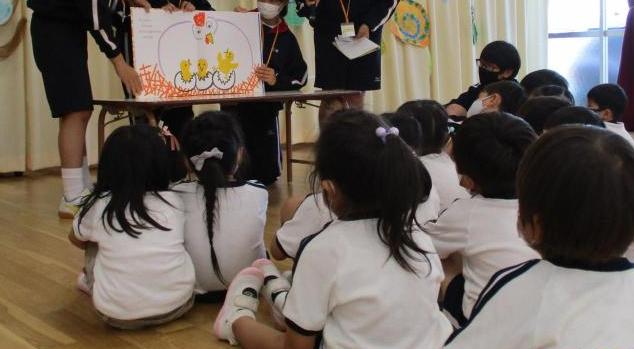 中学生が園児に大型絵本の読み聞かせをしている。