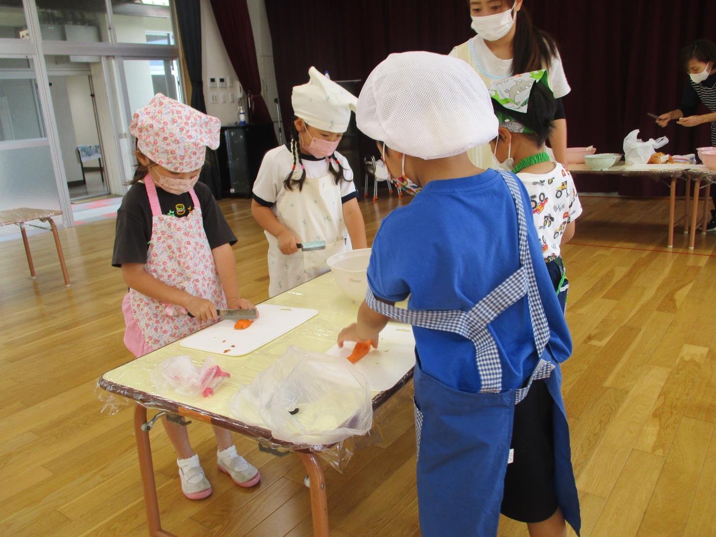 子ども達がニンジンやじゃがいもを包丁で切っている様子。