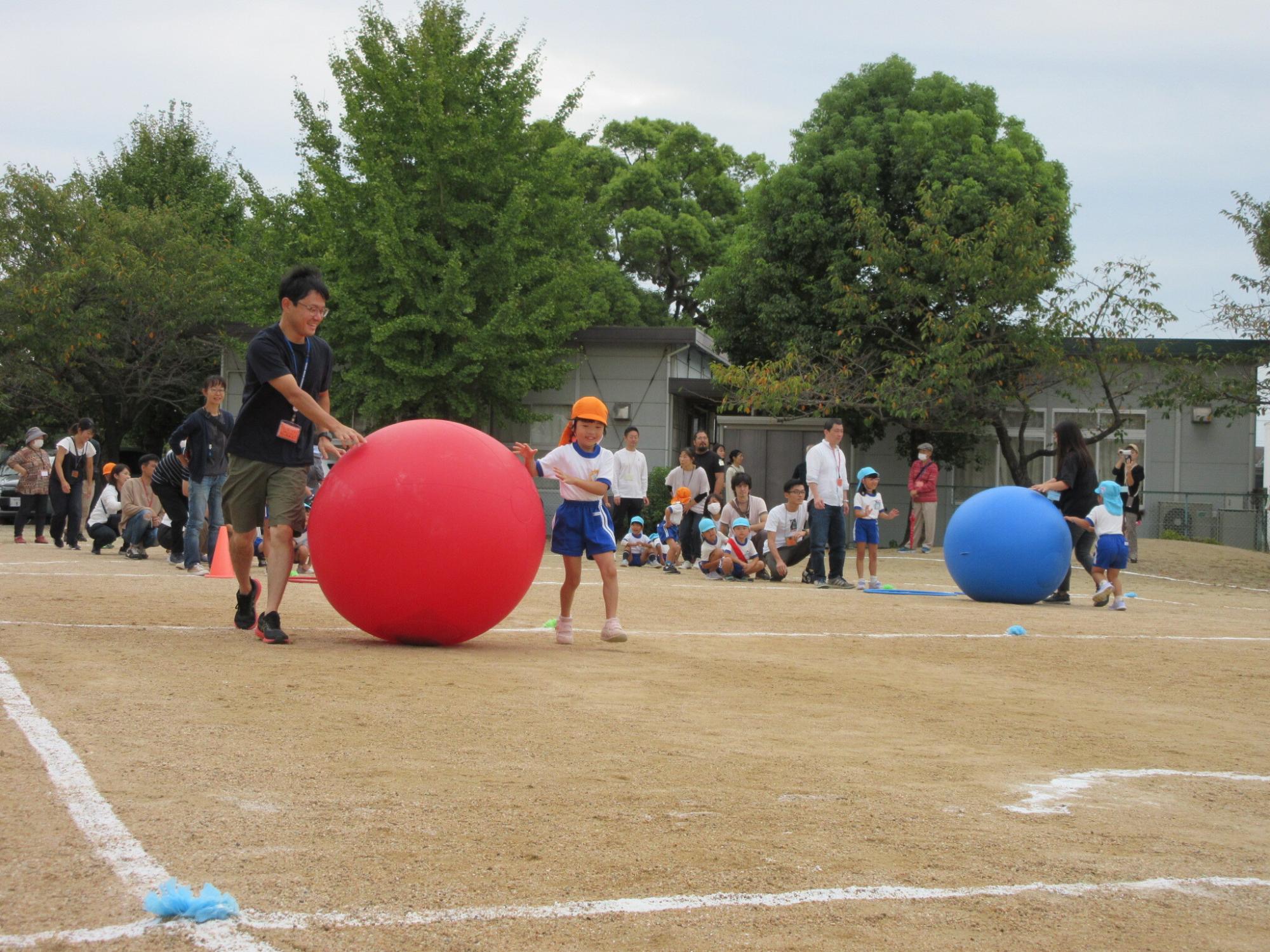 親子で大玉転がしリレーをする様子