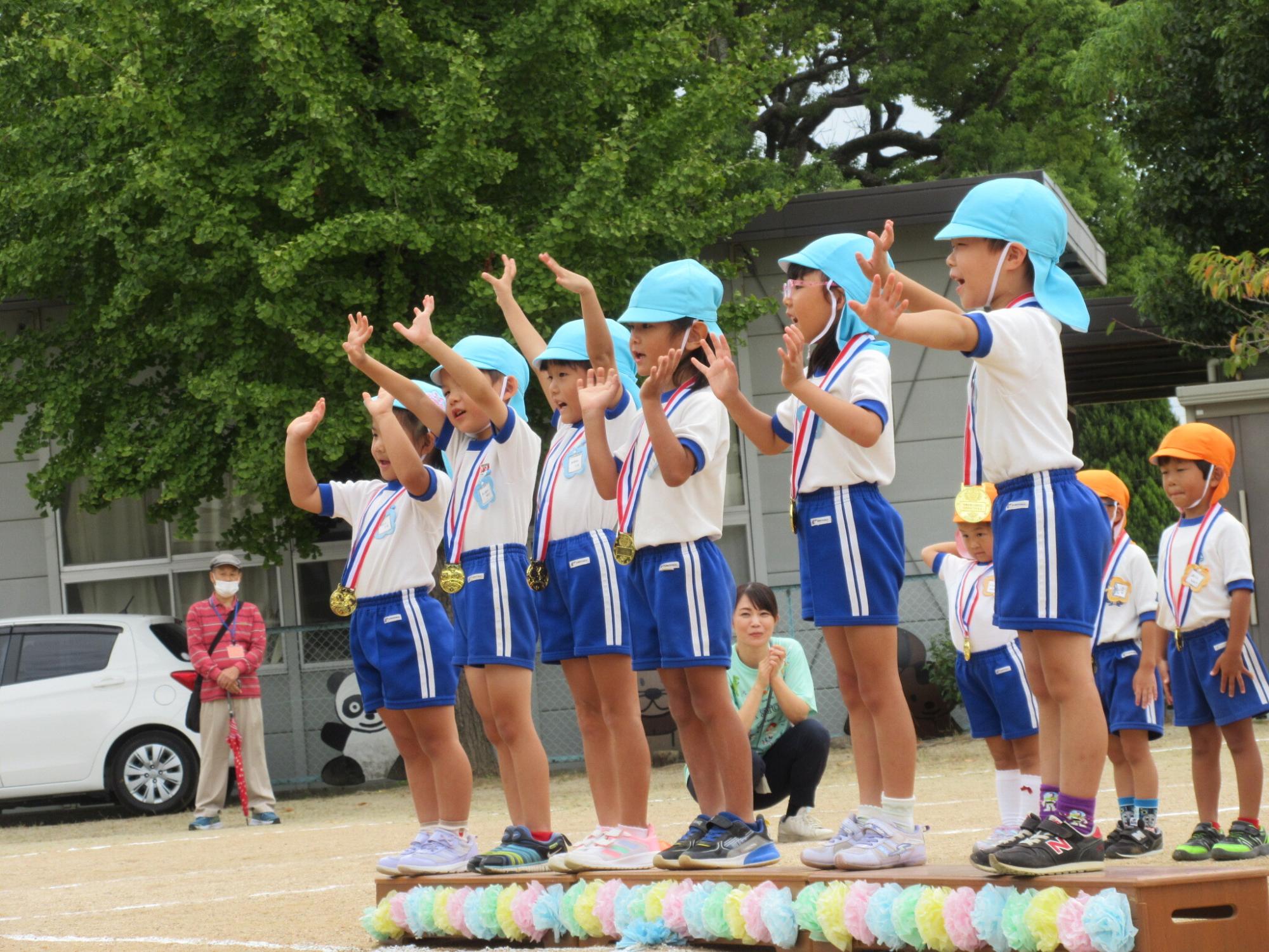 園長先生からメダルをかけてもらい、両手を挙げて喜ぶ園児たち