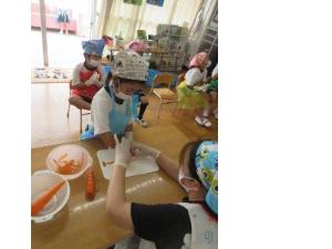 幼児がニンジンの皮をむいているところ