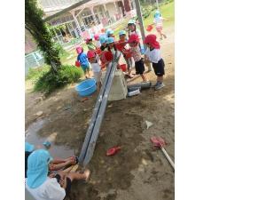 幼児が砂場で水を流しているところ