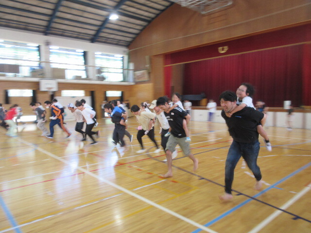 幼児が保護者におんぶをしてもらい走っている様子
