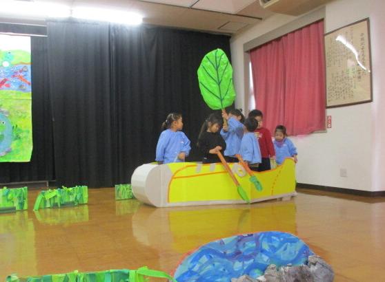 幼児が船に乗って小川を下る様子