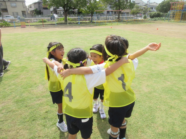 幼児がリレーのチームの仲間と掛け声をかけている様子