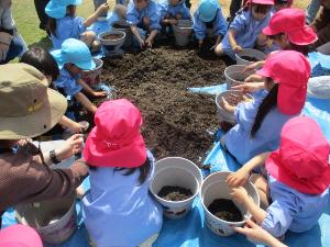 幼児が植木鉢に土を入れているところ