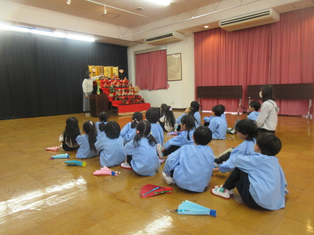 幼児がひな人形の由来の話を聞いている様子