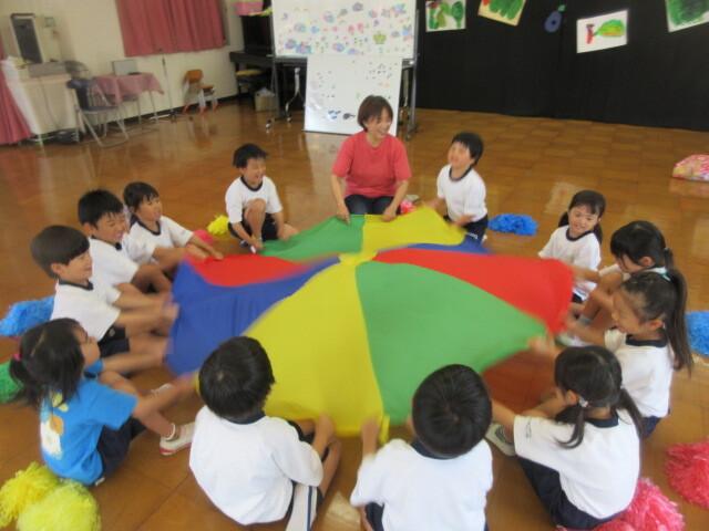 幼児が音楽に合わせてパラバルーンで遊んでいる様子