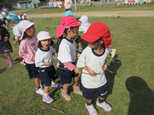 幼児がサツマイモのツルで遊んでいるところ