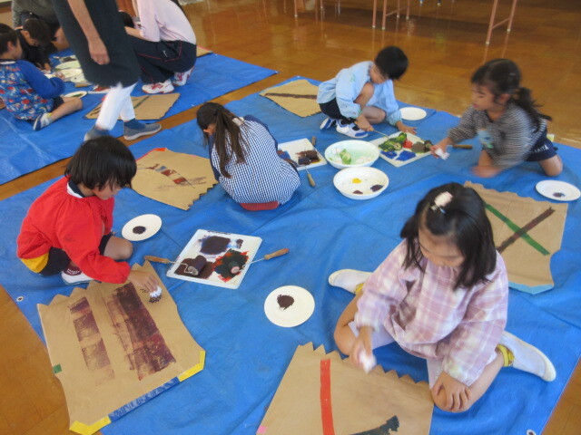 幼児がローラーで米袋に模様を描いている様子