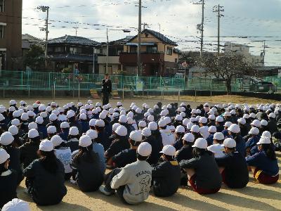 運動場に避難して校長先生の話を聞く児童