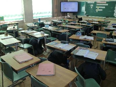 避難訓練で机の下に一時避難する児童