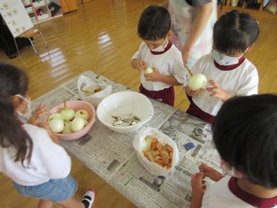 園児たちが玉ねぎの皮をむく様子です。
