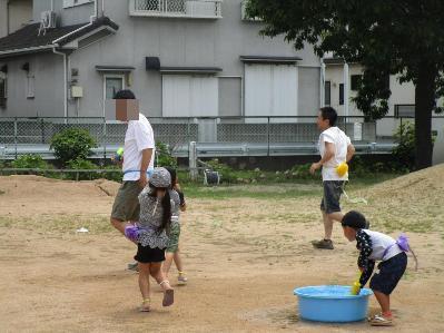 お父さんと水鉄砲を使ったしっぽとりをする様子です。
