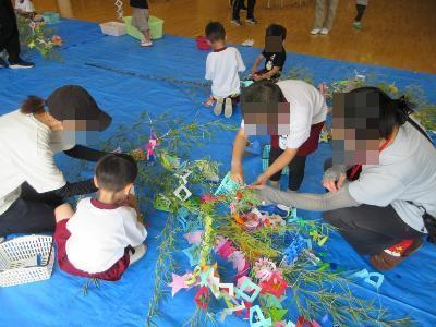 こども達とお家の人が笹飾りをつける様子です。