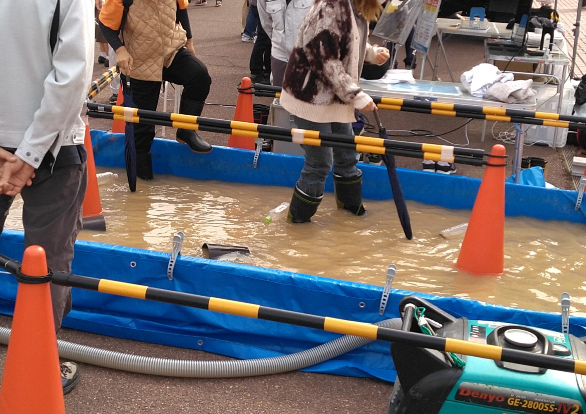 道路が浸水した状態を再現し、その中を歩く体験をしている。
