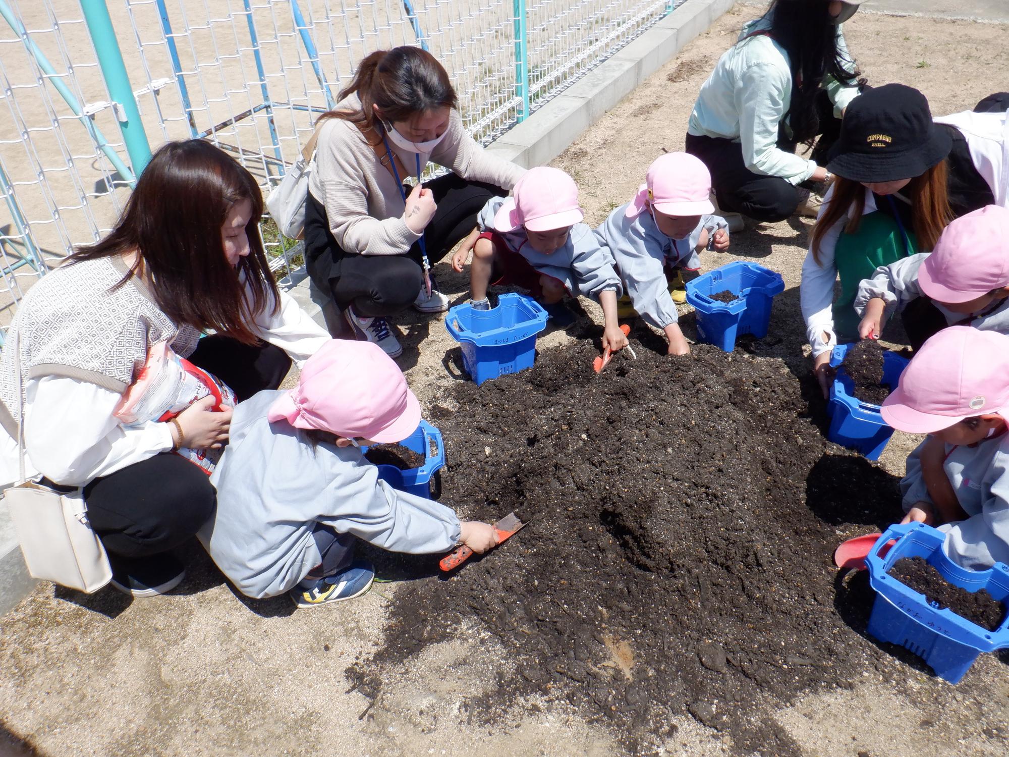 植木鉢に土を入れるはな組の子供と保護者