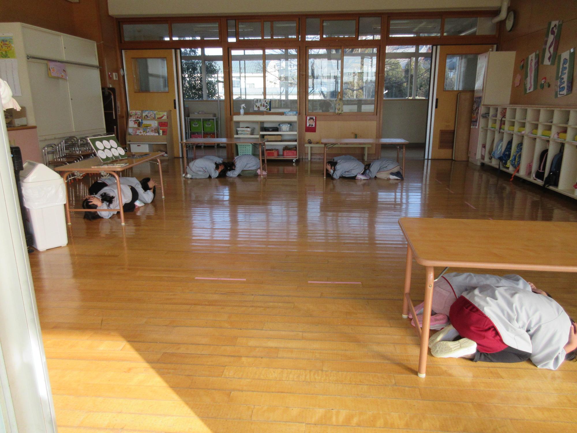 机の下に隠れる