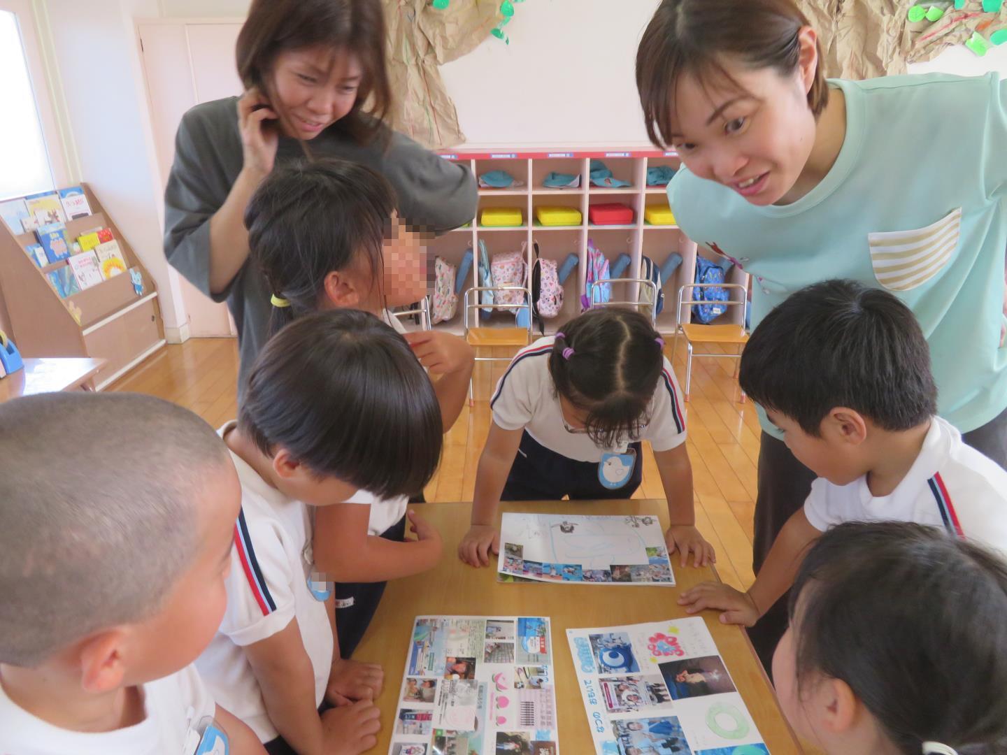 友達の思い出の絵や写真を見ている園児