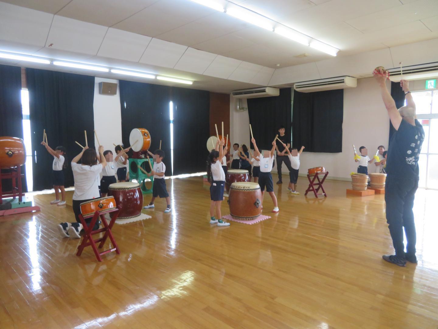 講師の先生を真似て腕をまっすぐ上に伸ばしている園児