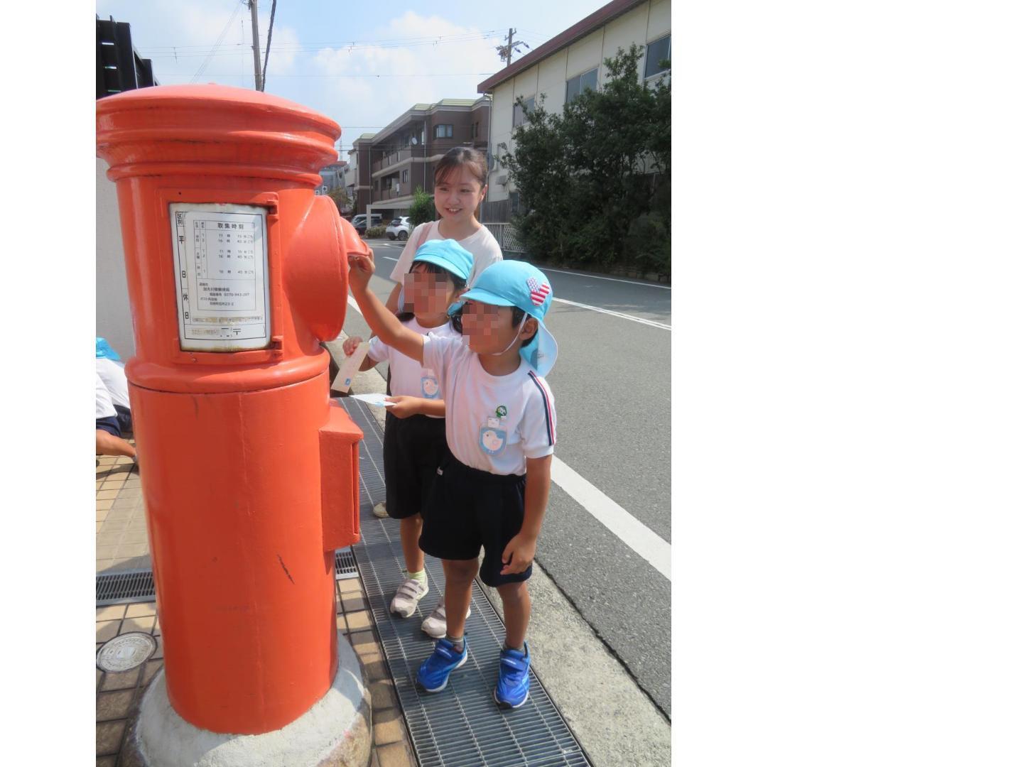 郵便ポストに手紙を投函している園児