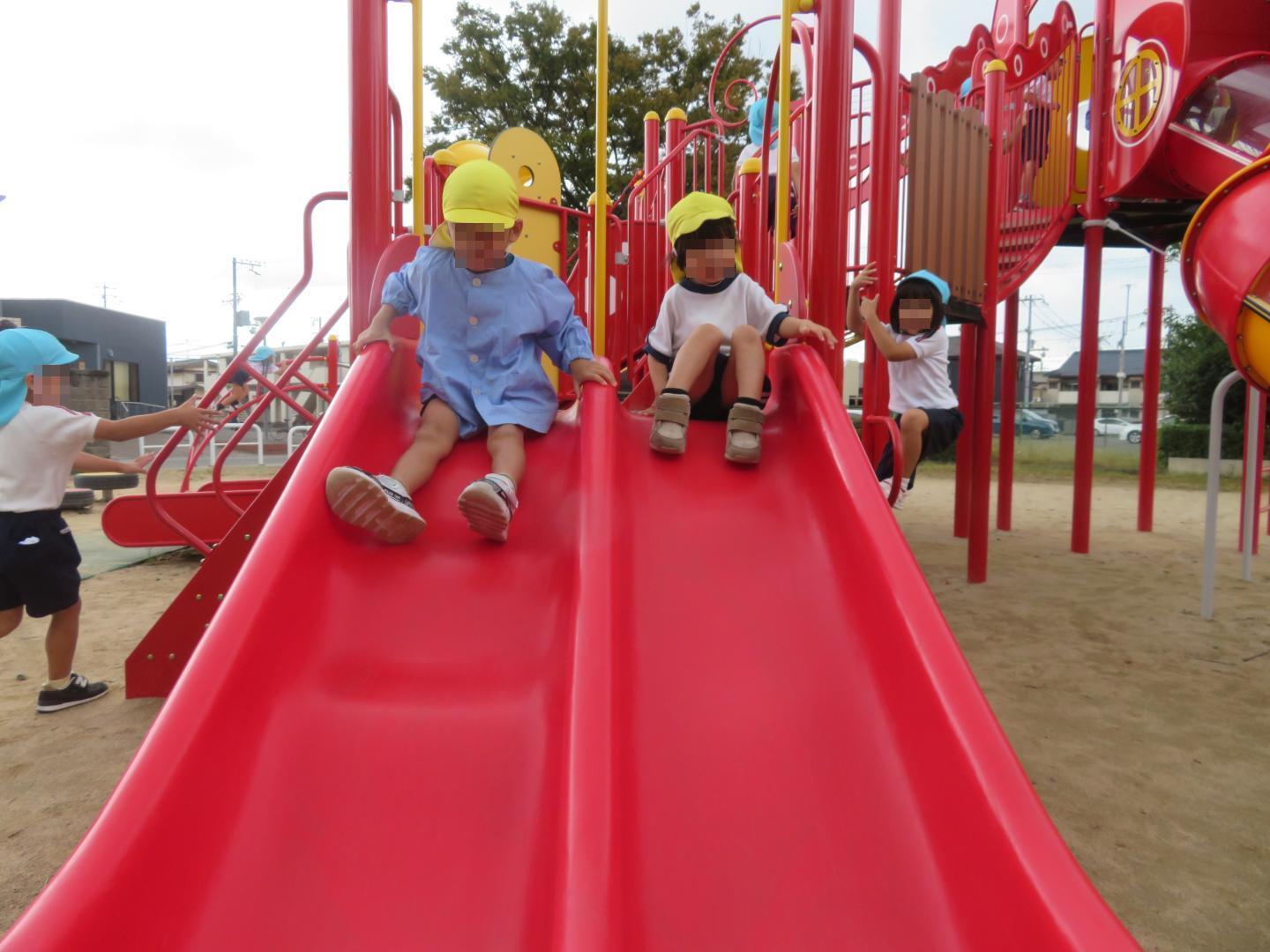 小さな滑り台を滑っている年少児