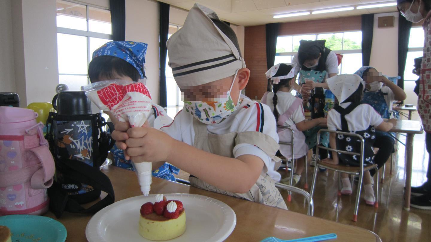 ケーキにホイップをトッピングする園児