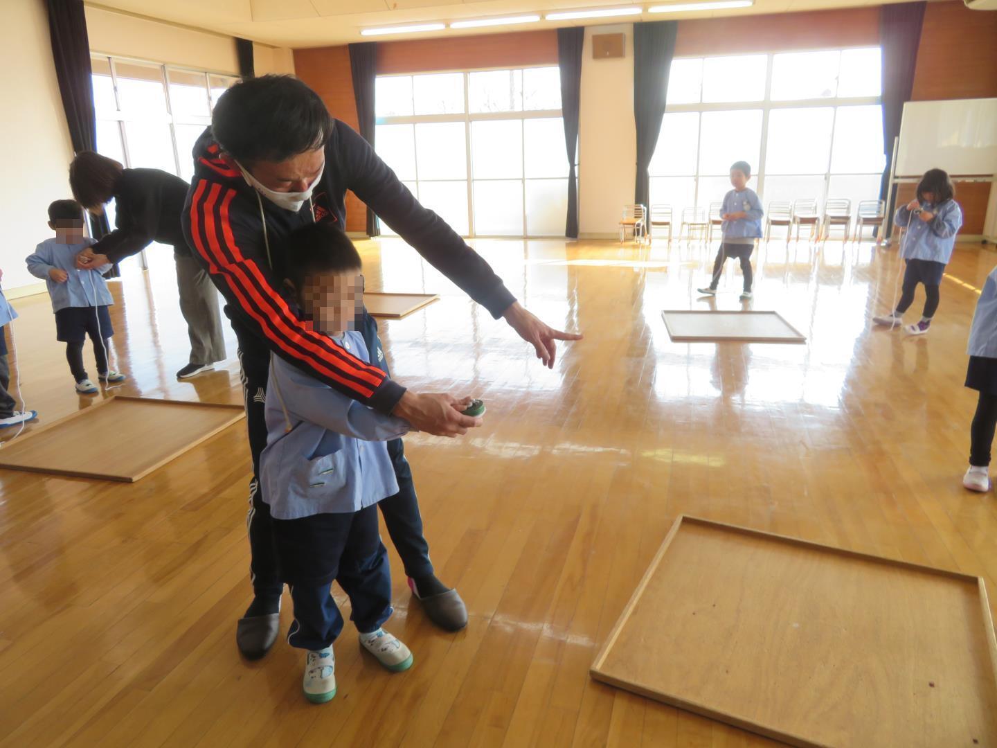 こま回し名人に個別にこまの回し方を教わる年長児