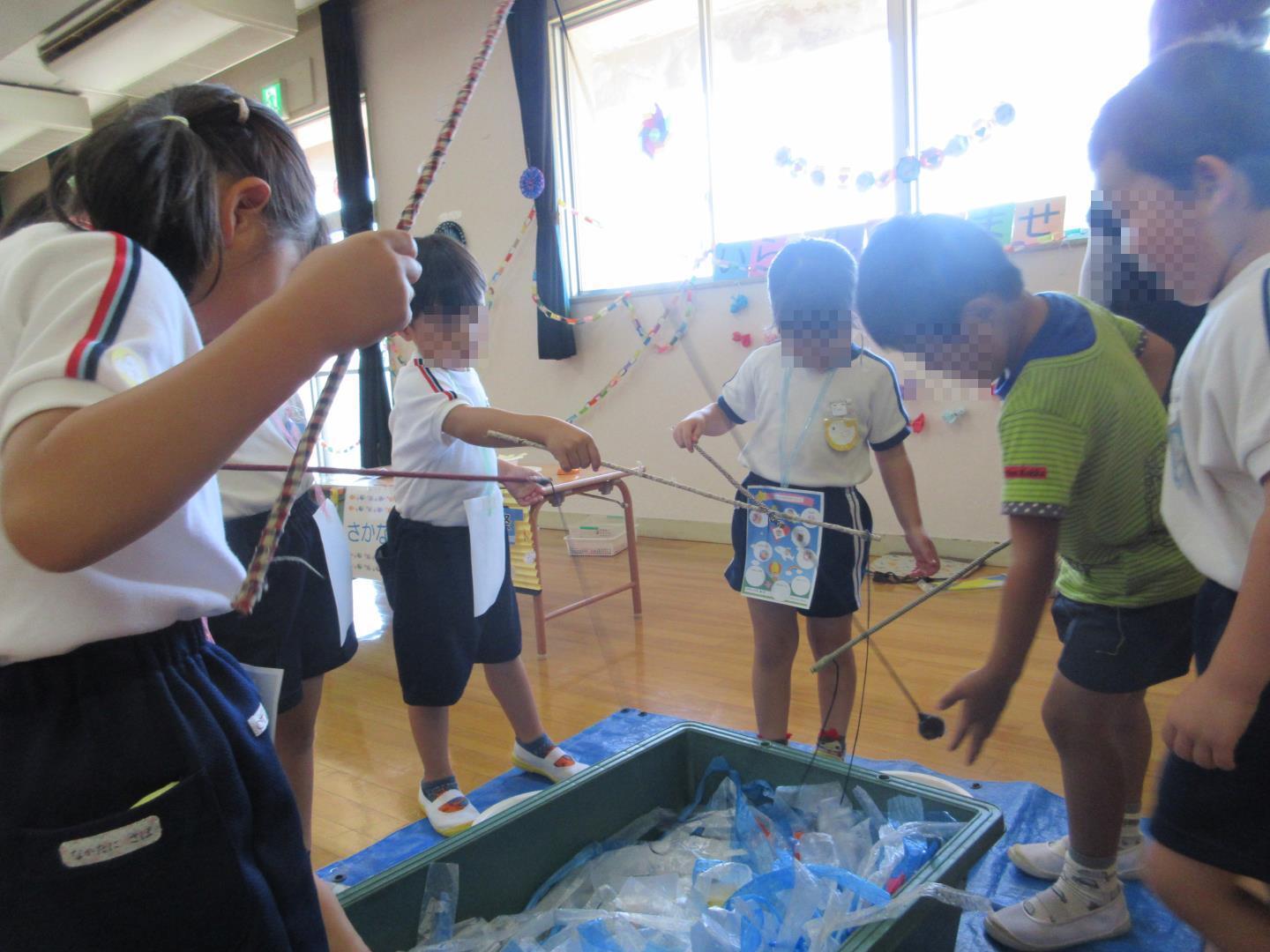 折り紙の魚を釣って遊ぶ園児