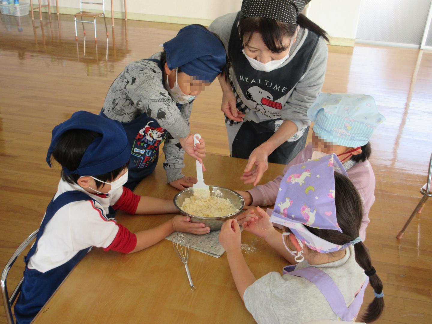 協力して生地を混ぜている幼児