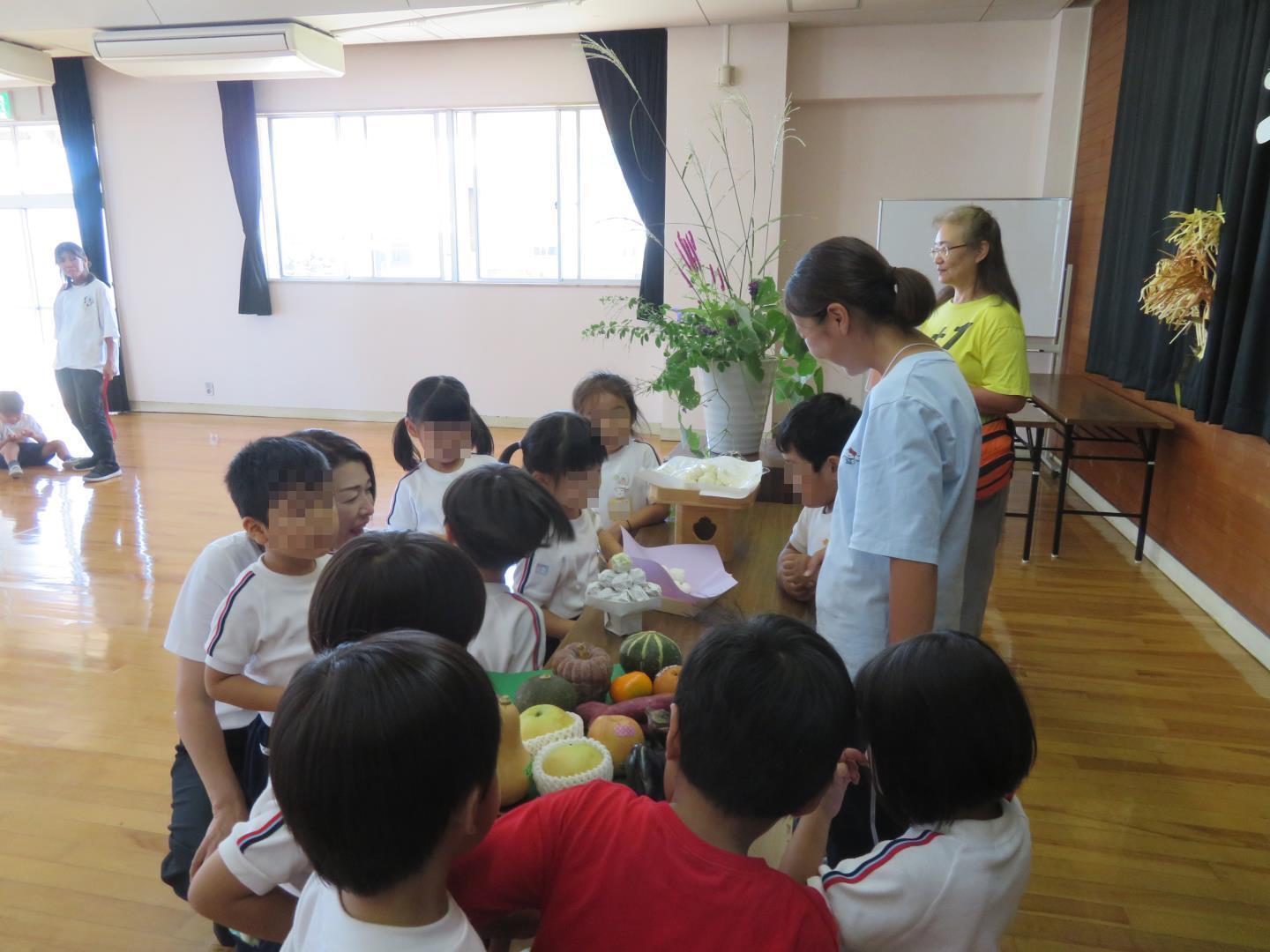 年少児が秋の作物や団子を見ているところ。