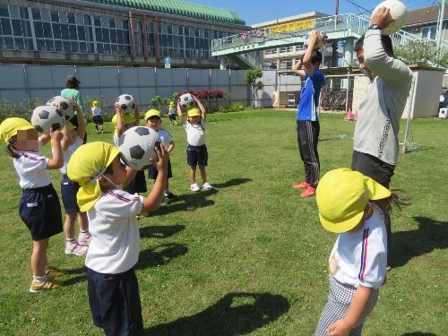 コーチの真似をしながら、ボールで遊んでいる様子