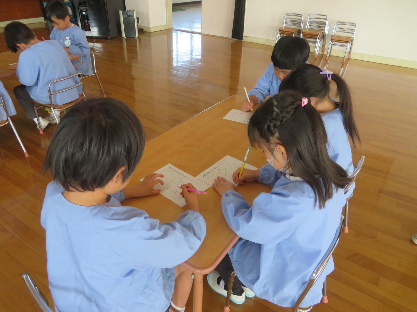 姿勢に気を付けながら鉛筆の練習をする幼児