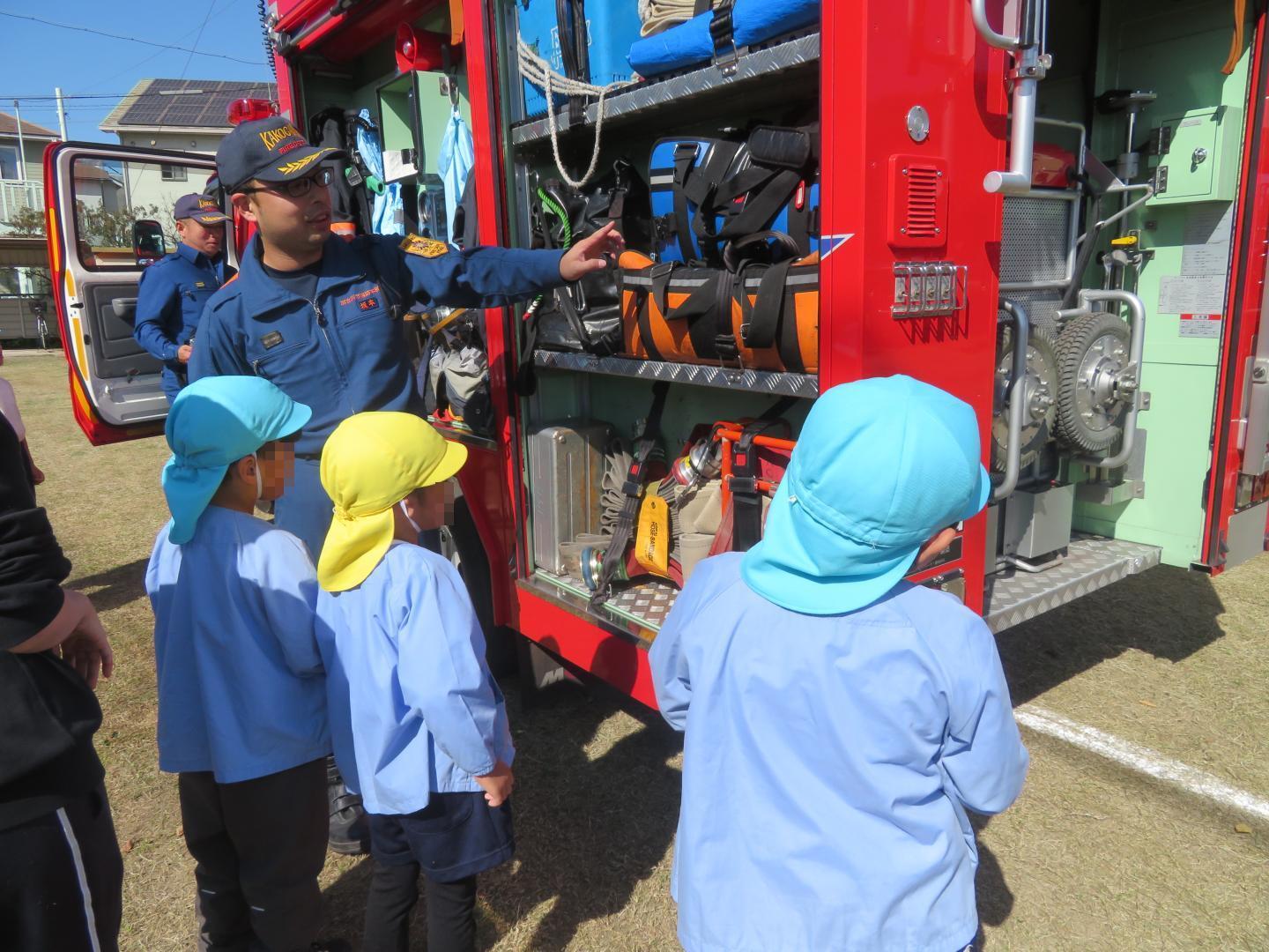 消防車に積んでいる道具の説明を聞く園児