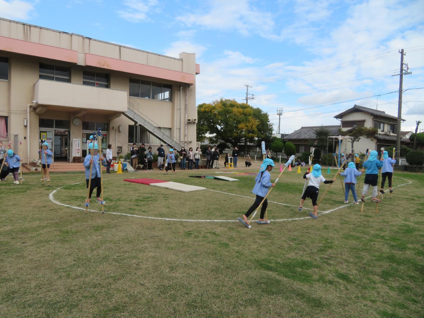 年長児が竹馬でトラックを行進している様子