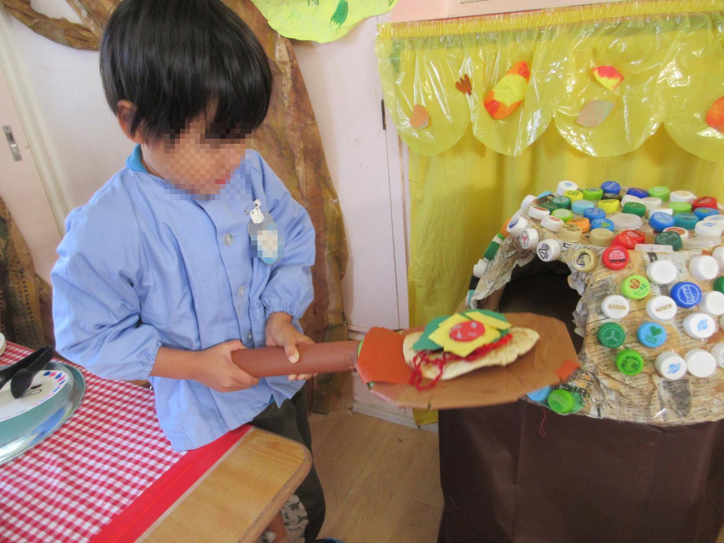 ピザ屋さんごっこで、作ったピザ窯でピザを焼いて遊んでいるところ