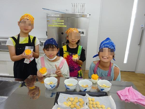 できあがったプリンとクッキーを見せる4人の子どもたち