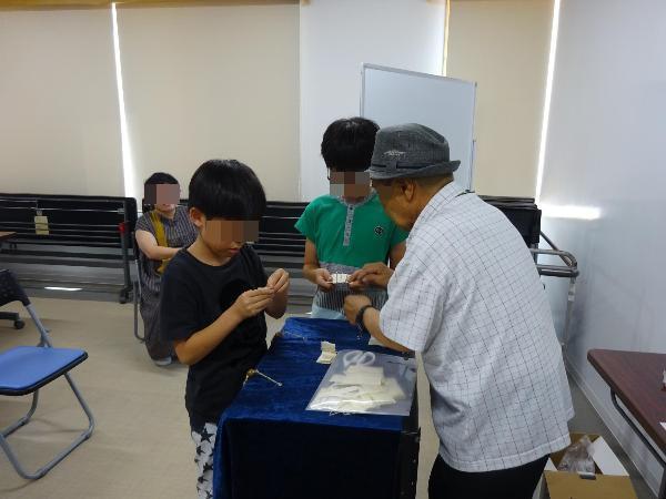 クリップを連結するマジックに挑戦する子どもたち