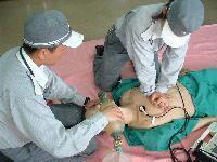 訓練用人形を用いて心臓マッサージの練習をする救急隊員の写真