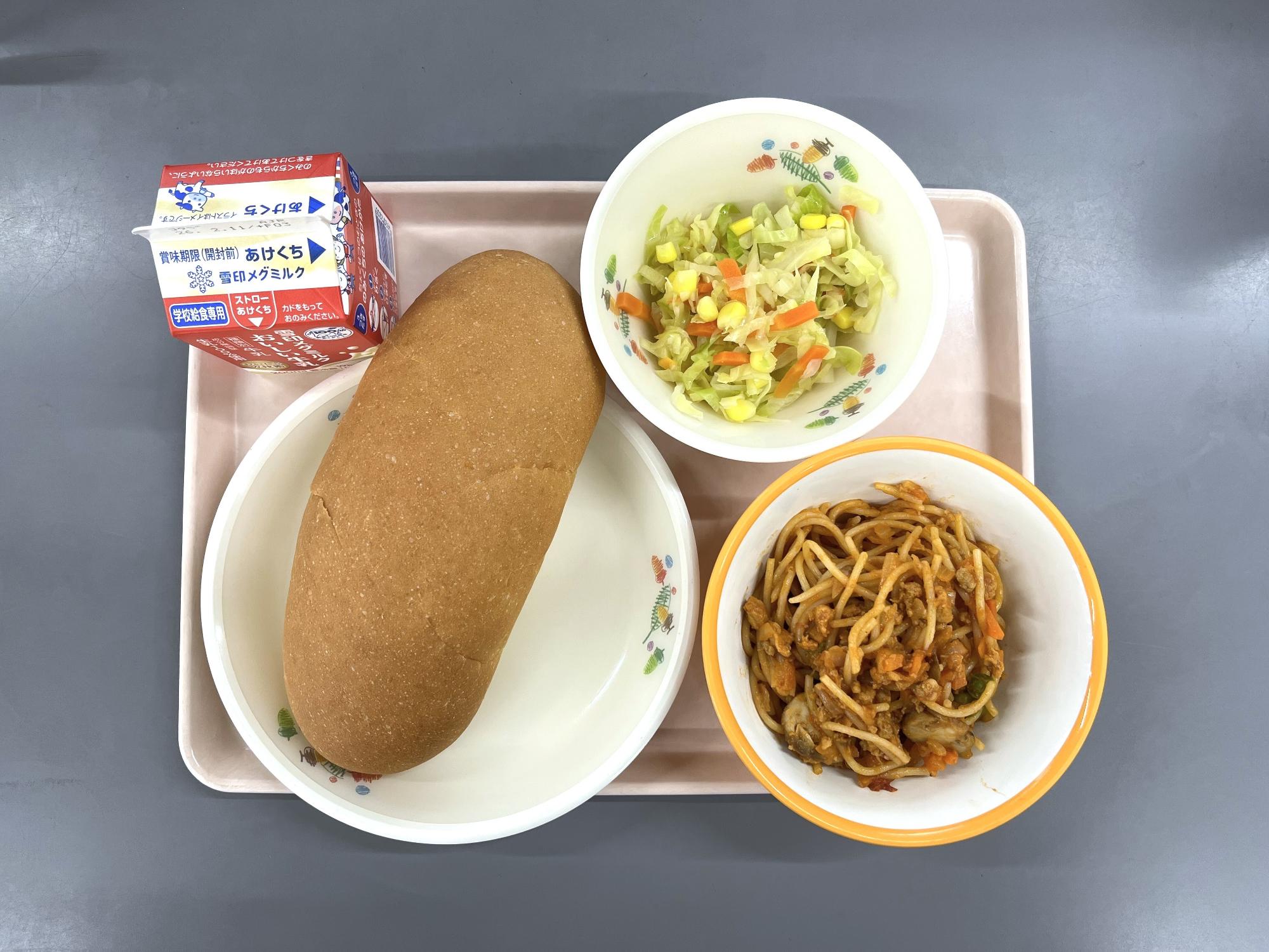 給食を上から撮影した写真。パン、牛乳、加古川パスタの大豆ミートスパゲティ、コーンサラダ