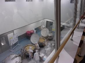 すまし汁の調理作業を2階の見学窓から見学している保護者
