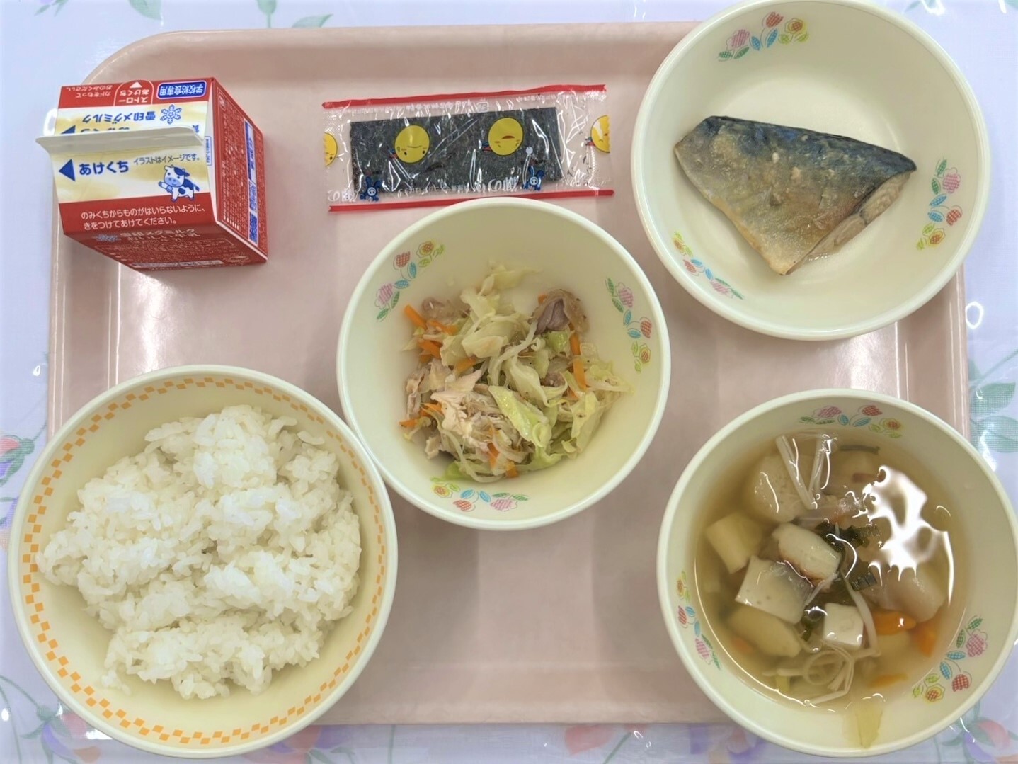 当日の給食を上から撮影した写真。ごはん、牛乳、鯖のレモンみそ煮、親鶏の甘酢和え、すまし汁、味付けのりが食器に盛られ、お盆に並んでいる。
