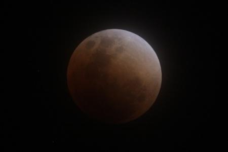 皆既状態に入ったばかりでうっすら赤く光る月の写真