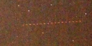夜空見えるたくさんの星の光の点とともに飛行機が通った跡が点になって見える写真